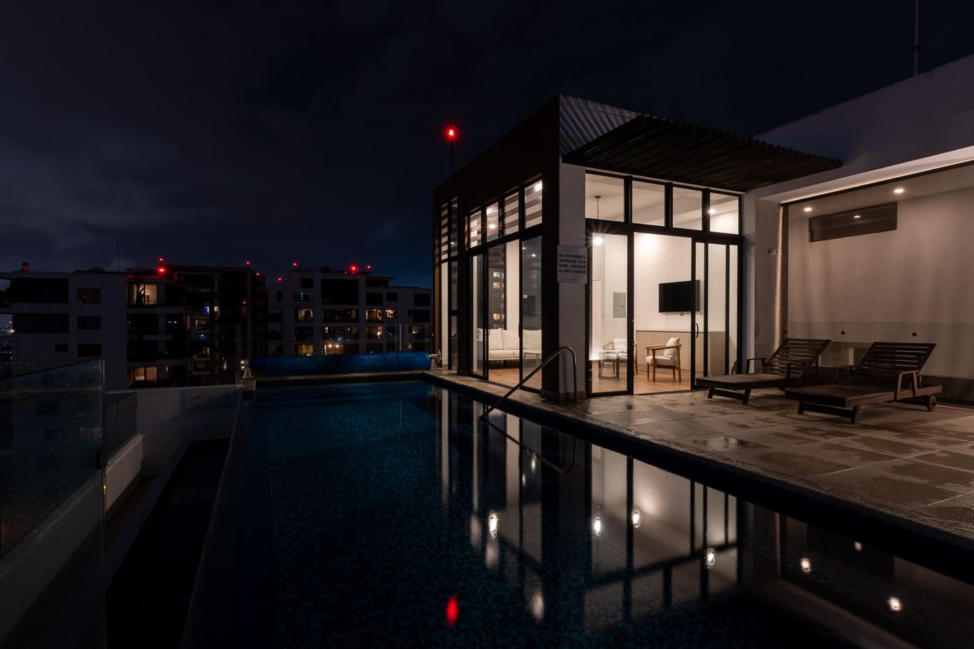 Final photo: Rooftop pool at night with the city behind it