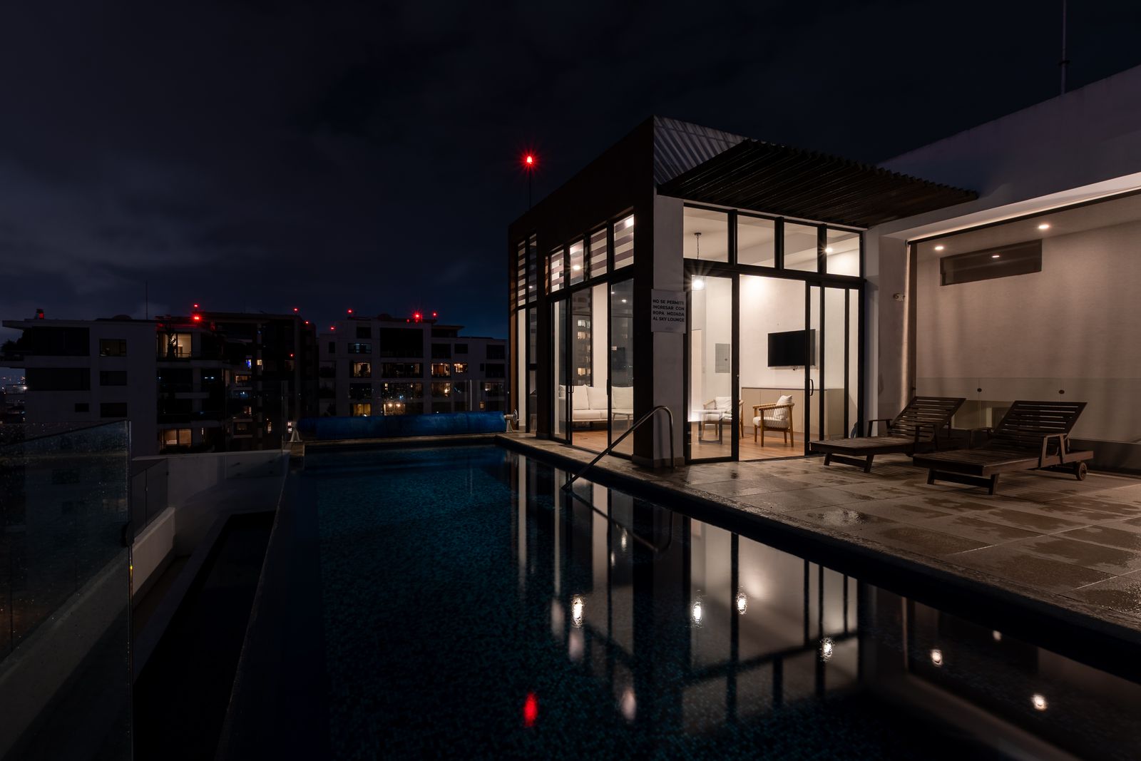 Rooftop pool at night with the city behind it